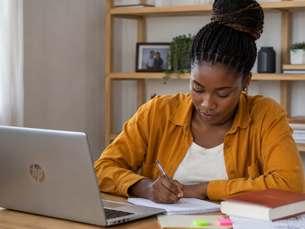 South African student working on an HP laptop while studying and managing an online side hustle from home.