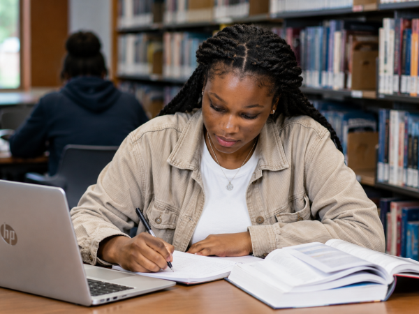 South African university student studying in a library with an HP laptop while applying for bursaries and scholarship opportunities