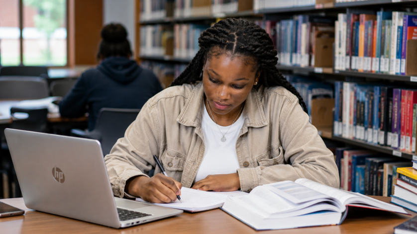 South African university student studying in a library with an HP laptop while applying for bursaries and scholarship opportunities